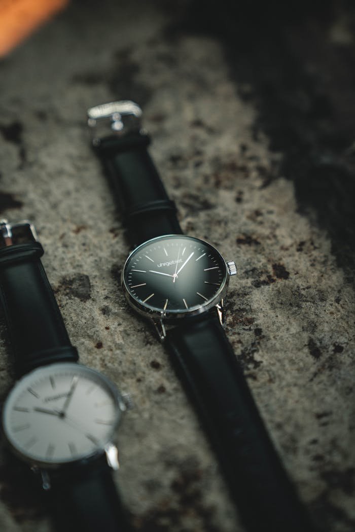 Home - Offiicial Stylish analog wristwatches with black leather straps displayed on a textured stone background.